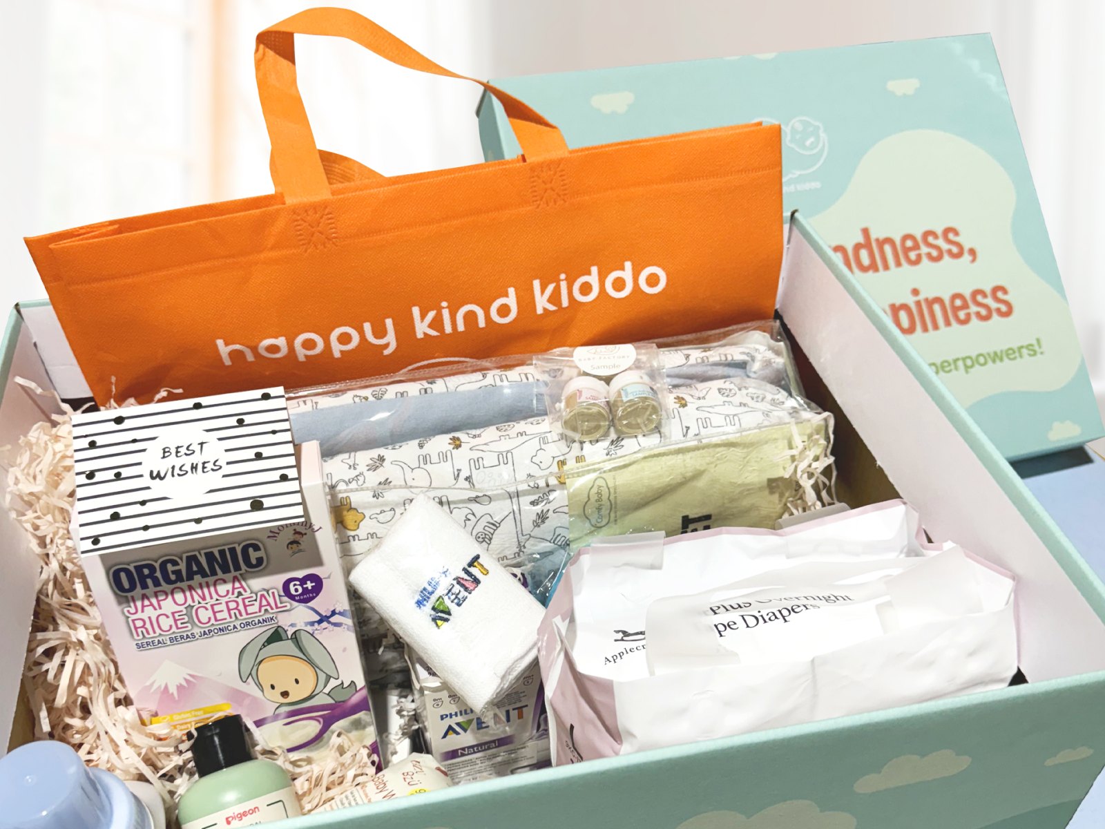 An open Happy Kind Kiddo gift box with our tote bag and the baby items packed inside